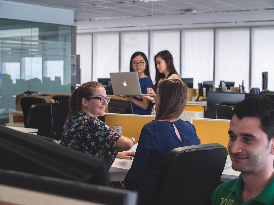 Two people looking at a laptop and two people smiling at each other, discussing what is RFP management.