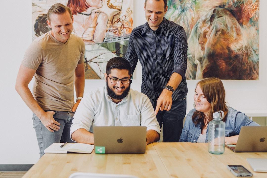 A procurement team looking at a laptop on a wooden table, smiling, learning about what is RFP management.